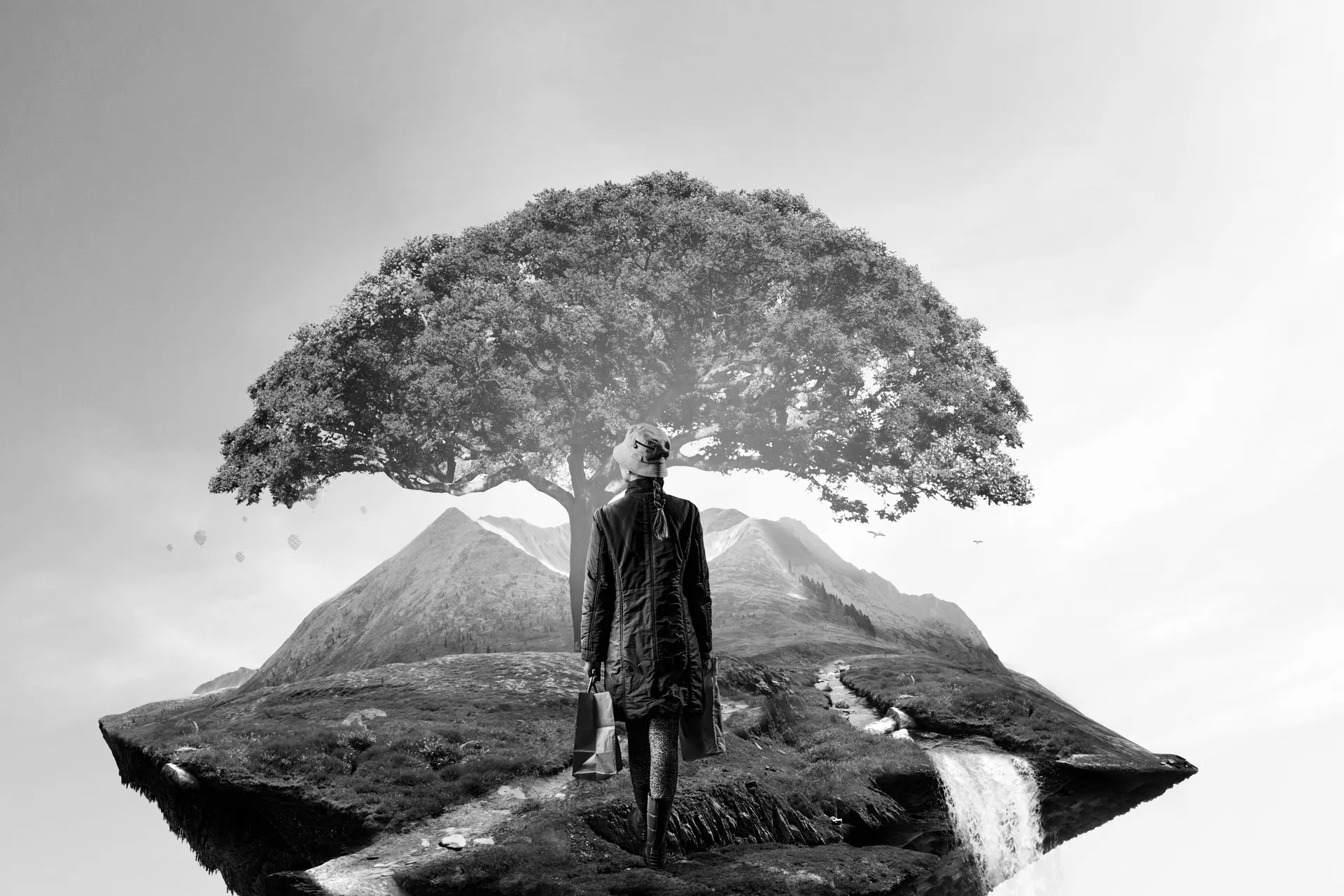 Frau vor einem großen Baum in einer Berglandschaft